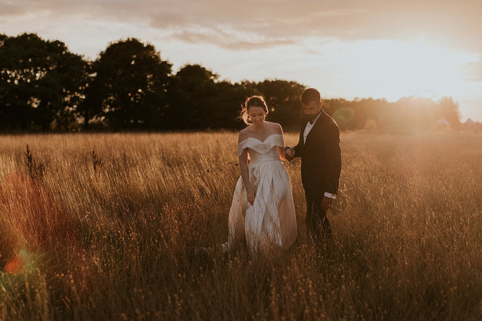 Couple walking through hay meadows at Elmley after their outdoor ceremony